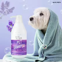 A small white dog wrapped in a light blue towel stands beside a bottle of pet shampoo on a purple background with lavender flowers and bubbles. The bottle label reads PET SHAMPOO, and the top right corner shows the brand name GUYE PET.